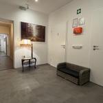 Flur mit Sitzbank, Lampenstand und Wandbild. Türen zu Badezimmern und weiteren Räumen.