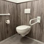 Toilette mit Handlauf und WC-Bedienung an der Wand