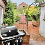 Terrasse mit Grill, Pflanzen und Blick auf eine Kirche