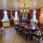 Esszimmer mit Holztisch, Stühlen, roten Vorhängen und Kronleuchter.