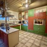 Küche mit grünen und roten Schränken, Edelstahlgeräten und Steinarbeitsplatten.