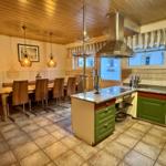 Küche mit Essbereich, grünen Schränken und Steinplatten.