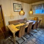 Esszimmer mit Holztisch, Stühlen und zwei Hängelampen über dem Tisch.