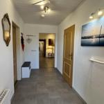 Flur mit Tür zu Wohnbereich, Wandbild und Handlauf an der Wand.