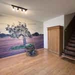 Eingangsbereich mit Holzboden, Wandbild, Holzschrank und Treppe.