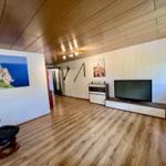 Wohnzimmer mit Holzboden, Fernseher und Wandbildern