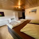 Schlafzimmer mit Doppelbett, Holzboden und Decke. Wandbild und Schrank sind sichtbar.