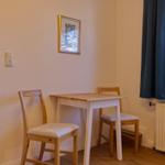 Essbereich mit Tisch, zwei Stühlen und Fenster mit Vorhang.