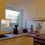 Küche mit Arbeitsplatte, Spüle, Kochfeld und Fenster.