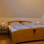 Ein Schlafzimmer mit einem Holzbett, zwei Nachttischen und einer geneigten Decke.