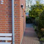 Haus mit rotem Backsteinfassade, weiße Bank und gepflasterte Gartentreppe.