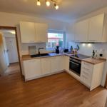 Küche mit weißen Schränken, Holzoberflächen und integriertem Ofen.