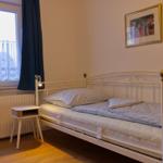 Ein Schlafzimmer mit Bett, Nachttisch und Fenster mit Vorhängen.