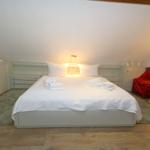 Bedroom with sloped ceiling, white bed, and red armchair.