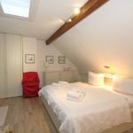 Bedroom with sloped ceiling, skylight, bed, wardrobe, and red armchair.