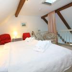 Bedroom with sloped ceiling, bed, two red chairs, and one armchair.