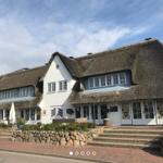 House with thatched roof, white walls and windows, entrance stairs and garden