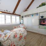 Living room with floral chairs, white cabinets, and wooden beam ceiling.