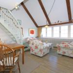 Living and dining area with hardwood floors, staircase, and floral armchairs.
