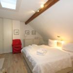 Attic room with bed, wardrobe, and sloped ceiling. Skylight and lamps provide light.