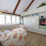Living room with wooden beam ceiling, white cabinets, and floral armchairs.