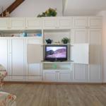 Living room with white cabinet, TV, and floral armchairs.