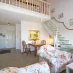 Living area with staircase, seating group, and dining area under sloped ceiling