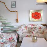 Living room with floral sofas, staircase, and wall painting of a red poppy.