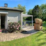 Wohnhaus mit Terrasse, Garten und Rattanliege. Eingangsbereich mit Blumen.