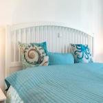 Schlafzimmer mit Bett, Kissen und Nachttisch. Wandbeleuchtung und weiße Wände.