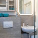 Badezimmer mit Waschbecken, Spiegel und Aufbewahrungskabinett. Türkis Handtücher und Laterne als Dekoration.