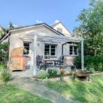 Terrasse mit Sitzgruppe, Grill und Wickerstuhl im Garten.