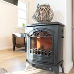 Ein elektrischer Kaminofen mit dekorativer Laterne darauf. Holzfußboden und Fenster im Hintergrund.