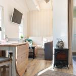 Wohn- und Essbereich mit Sofa, Tisch, TV und Kaminofen.