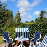 Terrace with blue and white lounge chairs and table under blue sky.