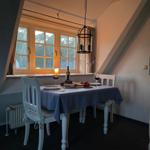 Dining room with table, chairs, and window. Hanging lamp and tablecloth.