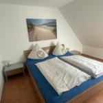 Schlafzimmer mit Doppelbett, Wandbild und zwei Nachttischen.