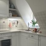 Küche mit weißen Schränken, Spüle und Herd. Dachfenster und Küchenzeile sichtbar.