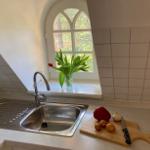 Küchenbereich mit Waschbecken, Fenster und Schneidebrett mit Zutaten.