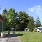 Haus mit strohgedecktem Dach, Garten mit Liegestühlen und Fahrrad.