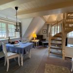 Essbereich mit Tisch, Stühlen und Fenster. Treppe führt zur oberen Etage.