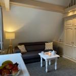 Wohnzimmer mit Sofa, Tisch und Schränken. Auf dem Tisch steht eine Teekanne.