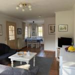 Wohn- und Essbereich mit Sofa, Tisch, Fernseher und Fenstern.