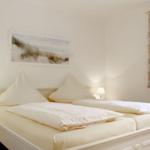 Schlafzimmer mit Doppelbett, zwei Nachttischen und Fenster mit Vorhang.