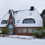 House with snow-covered roof and blue window frames.