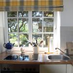 Kitchen with wooden countertop, window, and stove. Trees are visible outside.