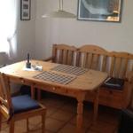 Wooden table with bench and chair, placemats, and wall art in dining room.