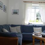 A living room with blue sofa, wooden table and window with white curtains.