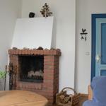 A fireplace with stones, a blue door, and a basket with wood.