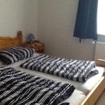 A bedroom with a wooden bed, striped bedding, and a nightstand with a lamp.